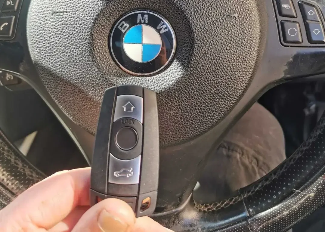 Hand holding a slim remote key beside a black steering wheel