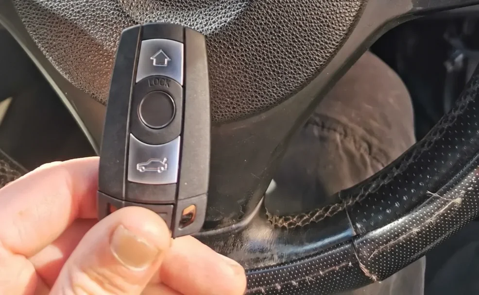 Hand holding a vehicle key inside a dark car interior